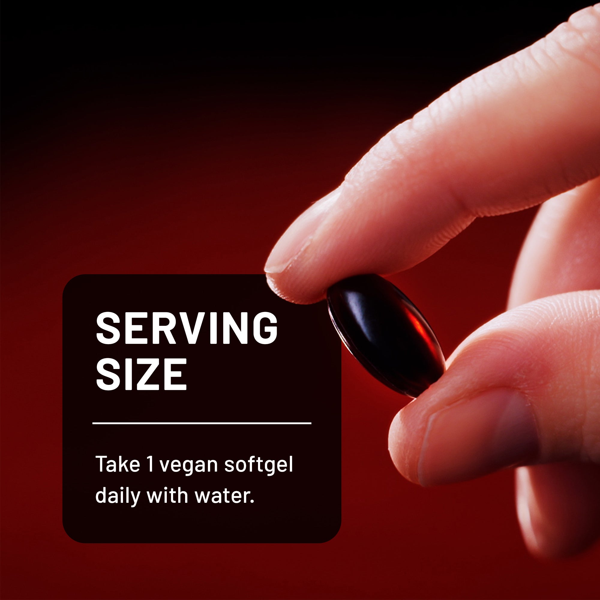 Hand holding a vegan astaxanthin softgel with serving size information on a red background