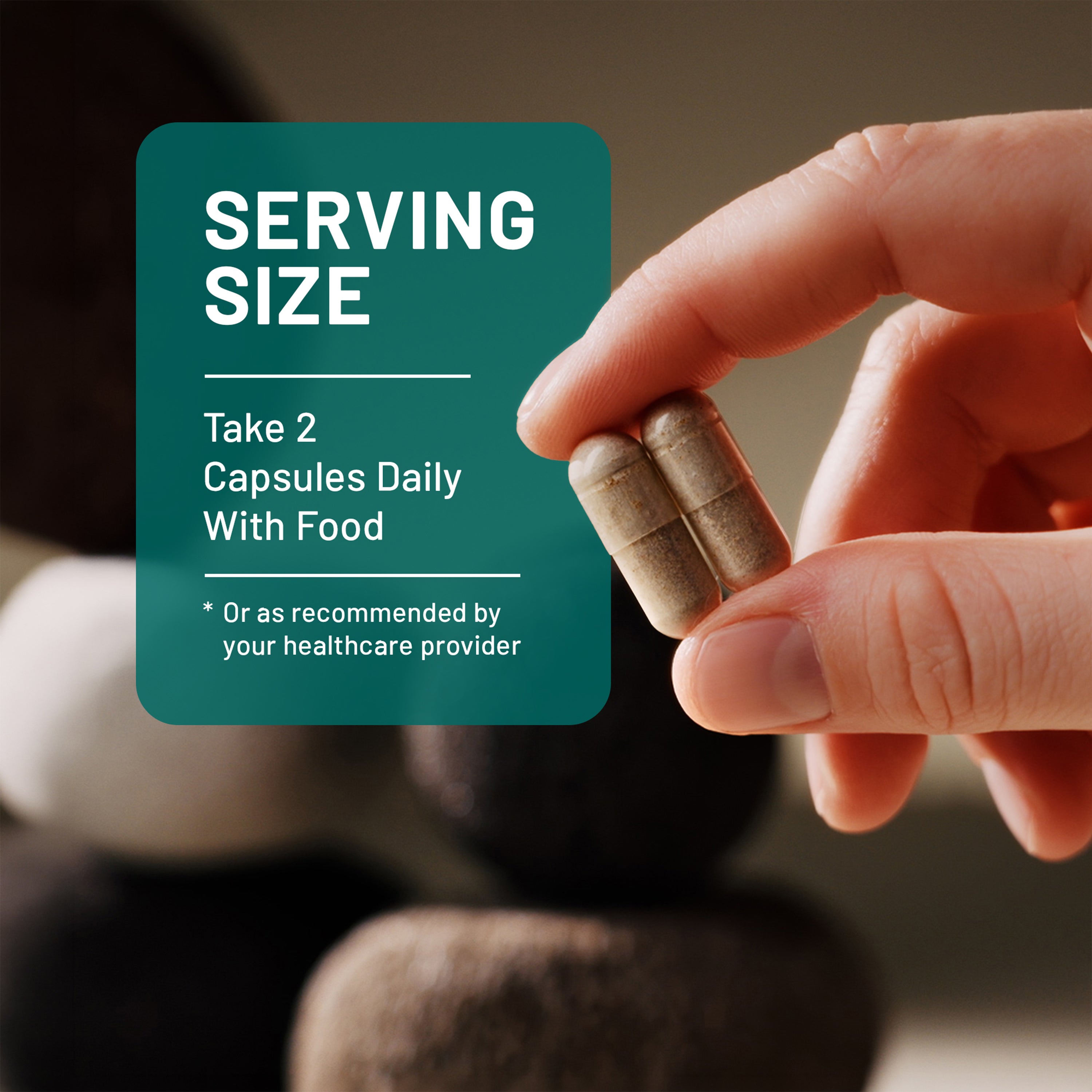 Hand holding two capsules with a label indicating serving size and daily recommendation.