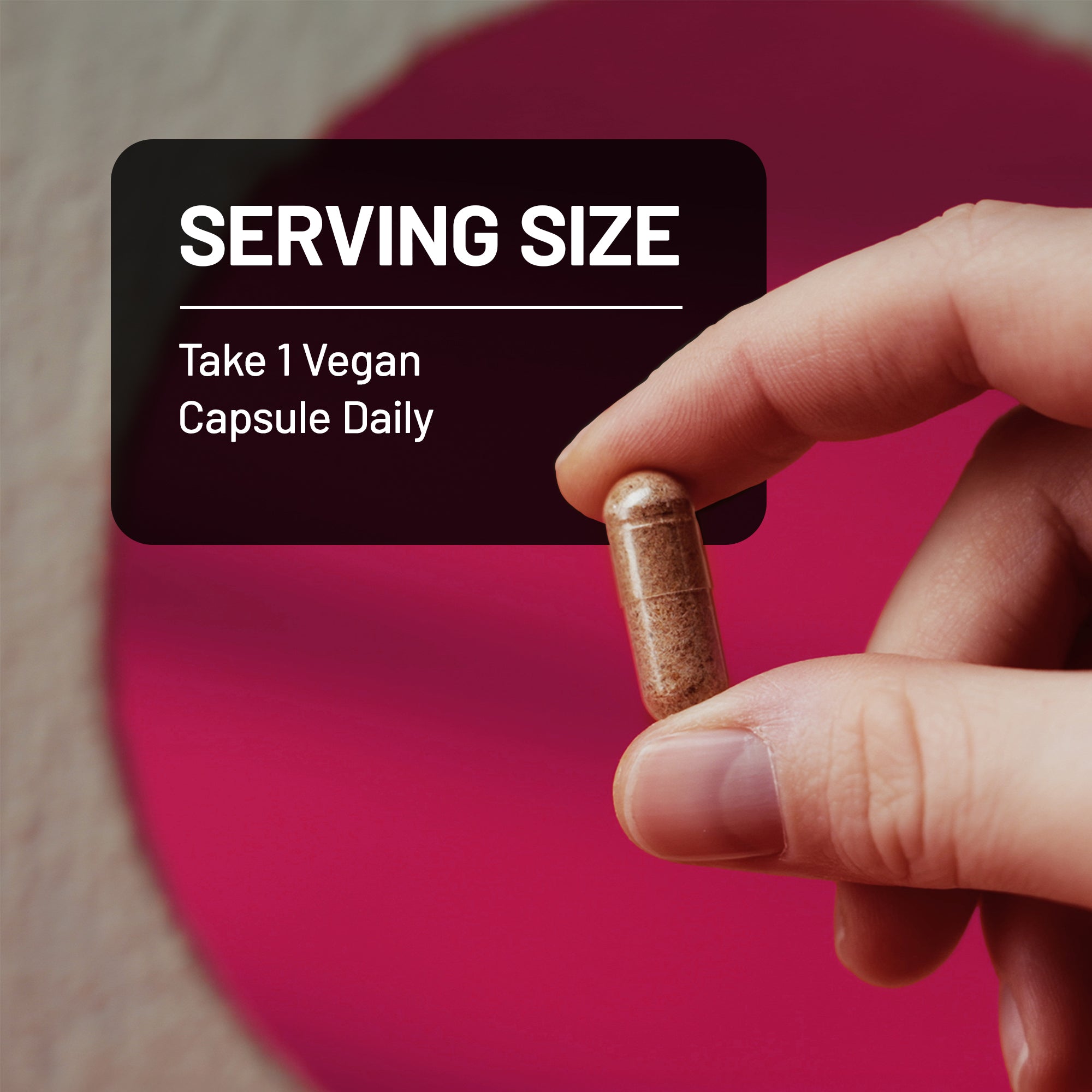 Hand holding a vegan capsule with text about serving size on a pink background