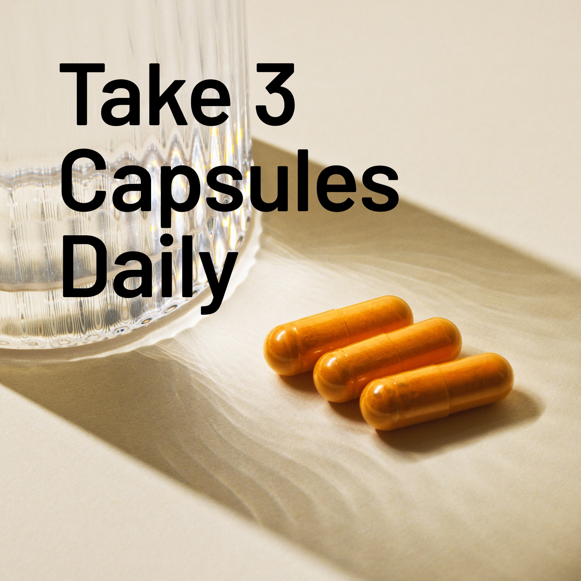 Three capsules on a light surface with text 'Take 3 Capsules Daily' and a glass container in the background.