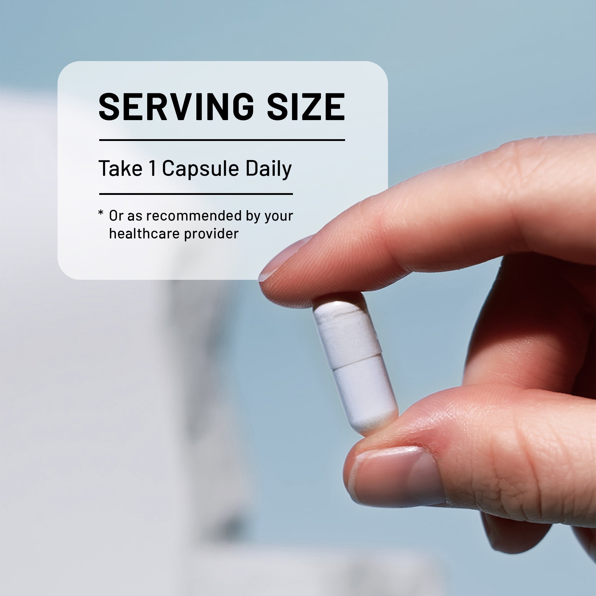 A close-up of a hand holding a white NatureWise Magnesium Citrate capsule pill, with an informational card that reads 'SERVING SIZE Take 1 Capsule Daily' against a soft light blue background.
