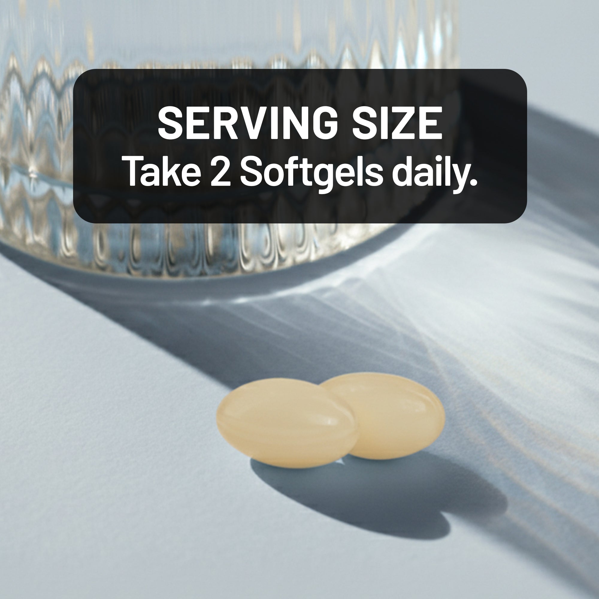Two softgels on a light surface with text indicating serving size.