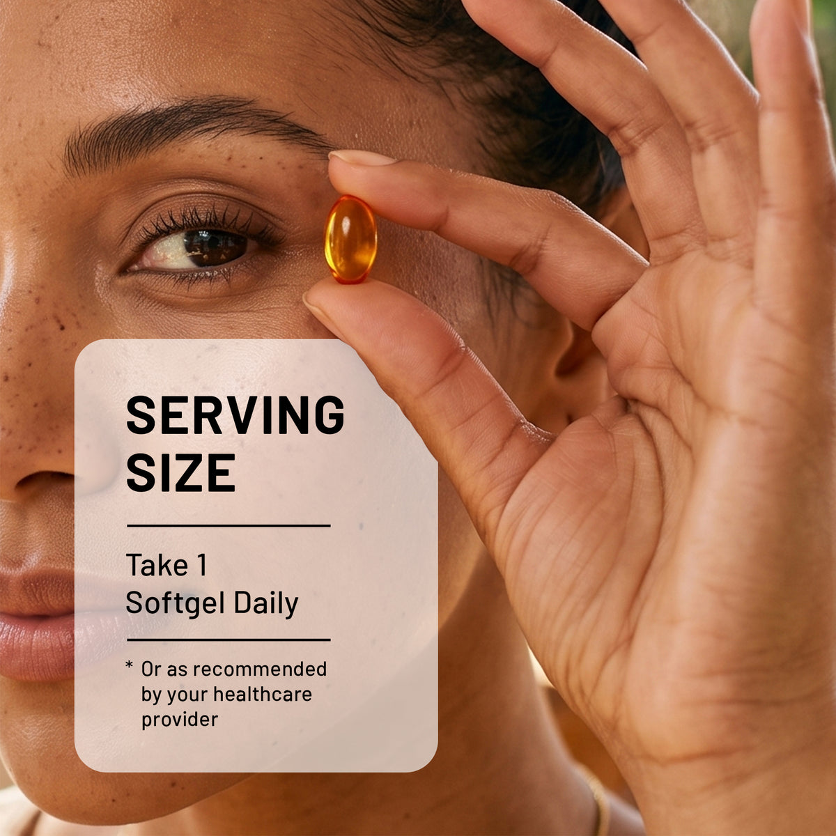 A close-up of a person holding a translucent orange softgel capsule near their eye, with an overlaid card reading 'SERVING SIZE: Take 1 Softgel Daily'.