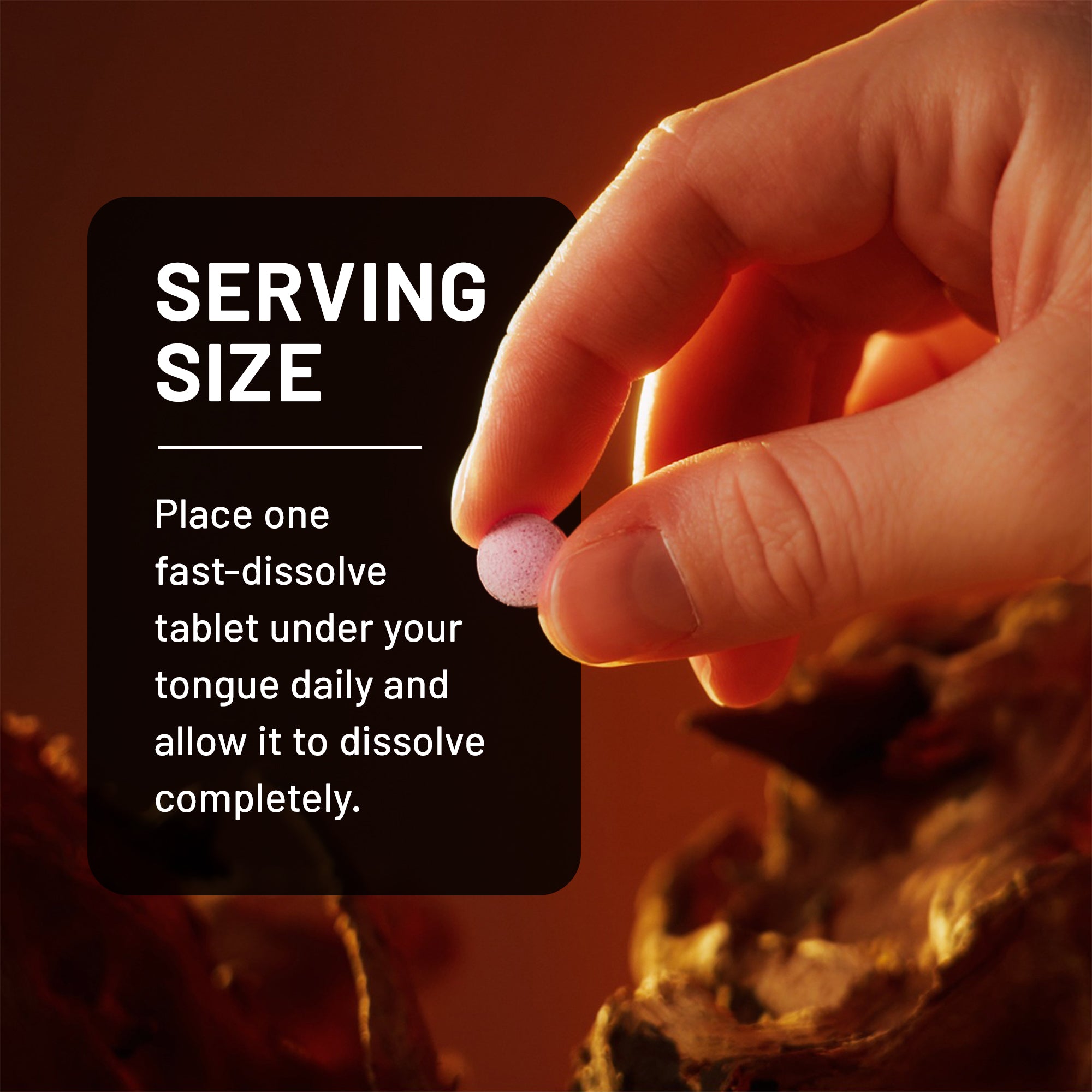 Hand holding a small pink sublingual D3 supplement tablet with text about serving size on a dark background