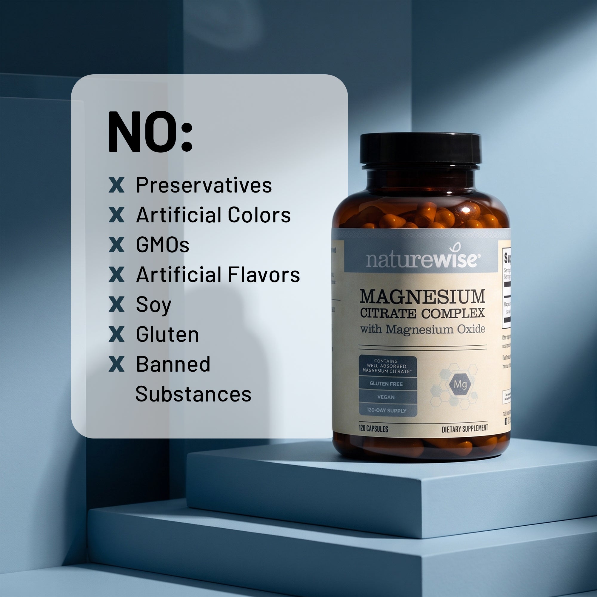 A bottle of Naturewise Magnesium Citrate Complex with magnesium oxide dietary supplement stands on blue display steps next to a white card listing excluded ingredients such as preservatives, artificial colors, GMOs, artificial flavors, soy, gluten, and banned substances.