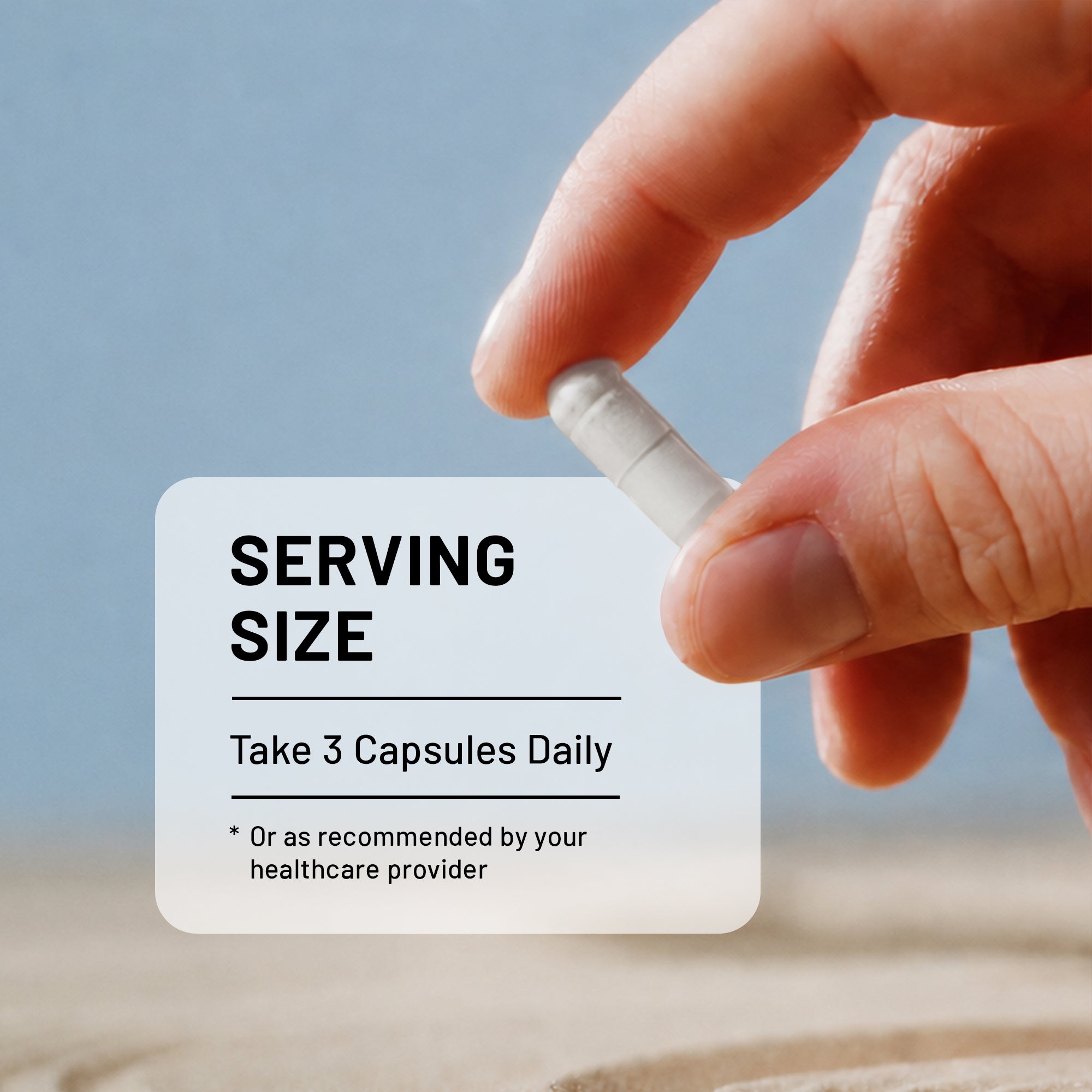 A close-up of a hand holding a white capsule pill in front of a soft-focus outdoor background. A semi-transparent label reads 'SERVING SIZE' and 'Take 3 Capsules Daily'.