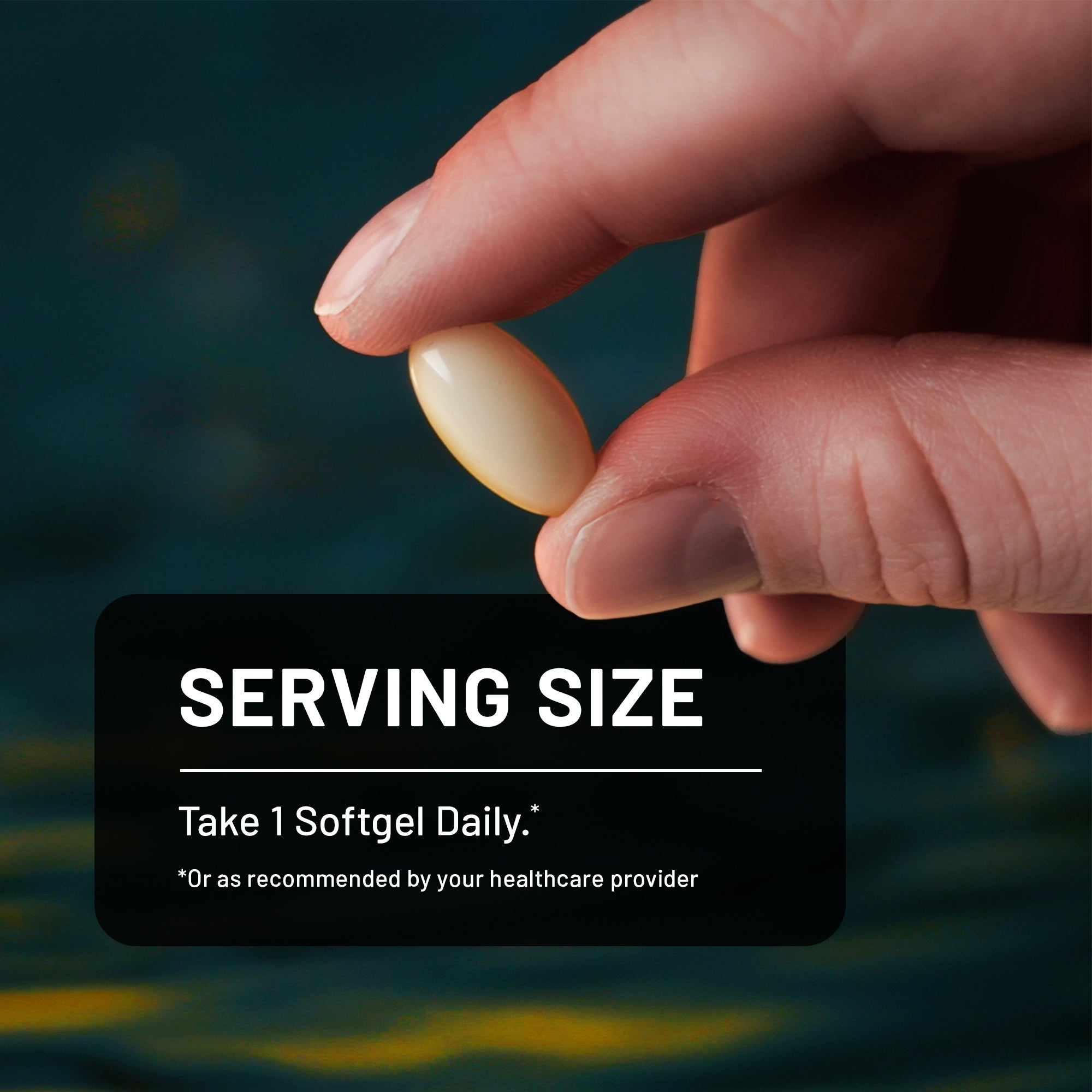 Hand holding a NatureWise Vitamin D3 K2 with magnesium softgel with serving size instructions on a blurred natural background