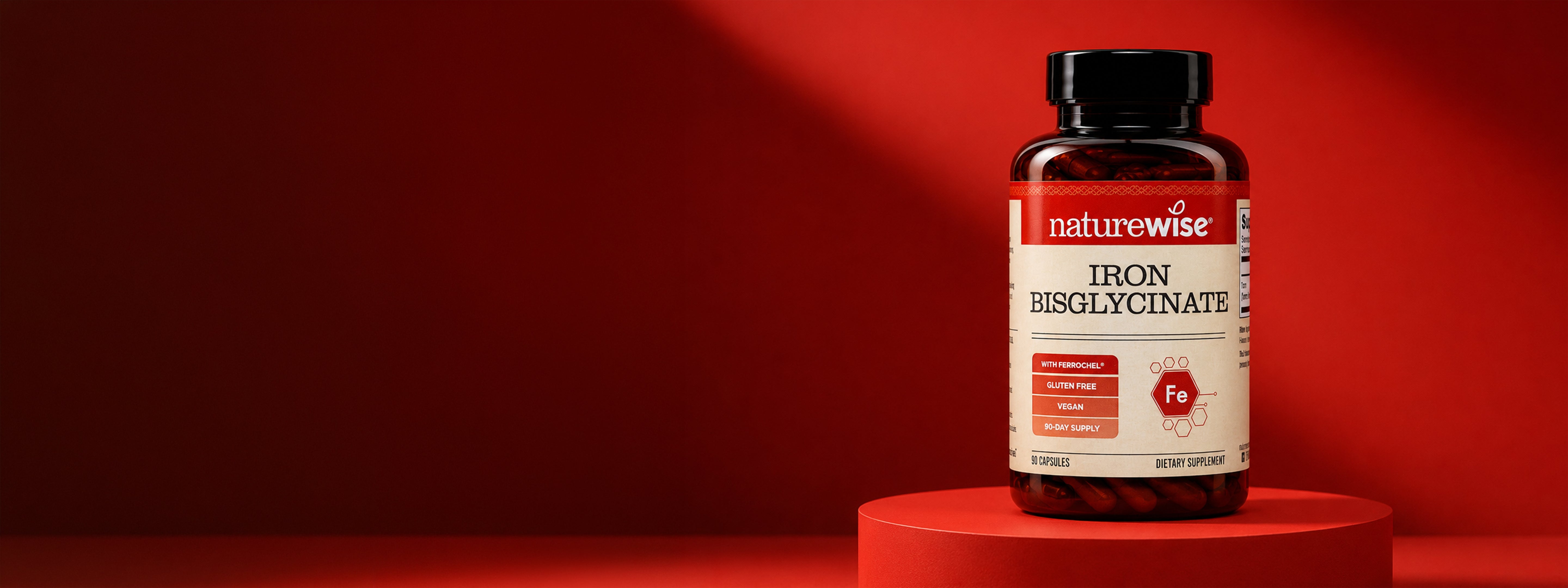 A bottle of Naturewise Iron Bisglycinate dietary supplements displayed on a matching red pedestal against a dark red background.
