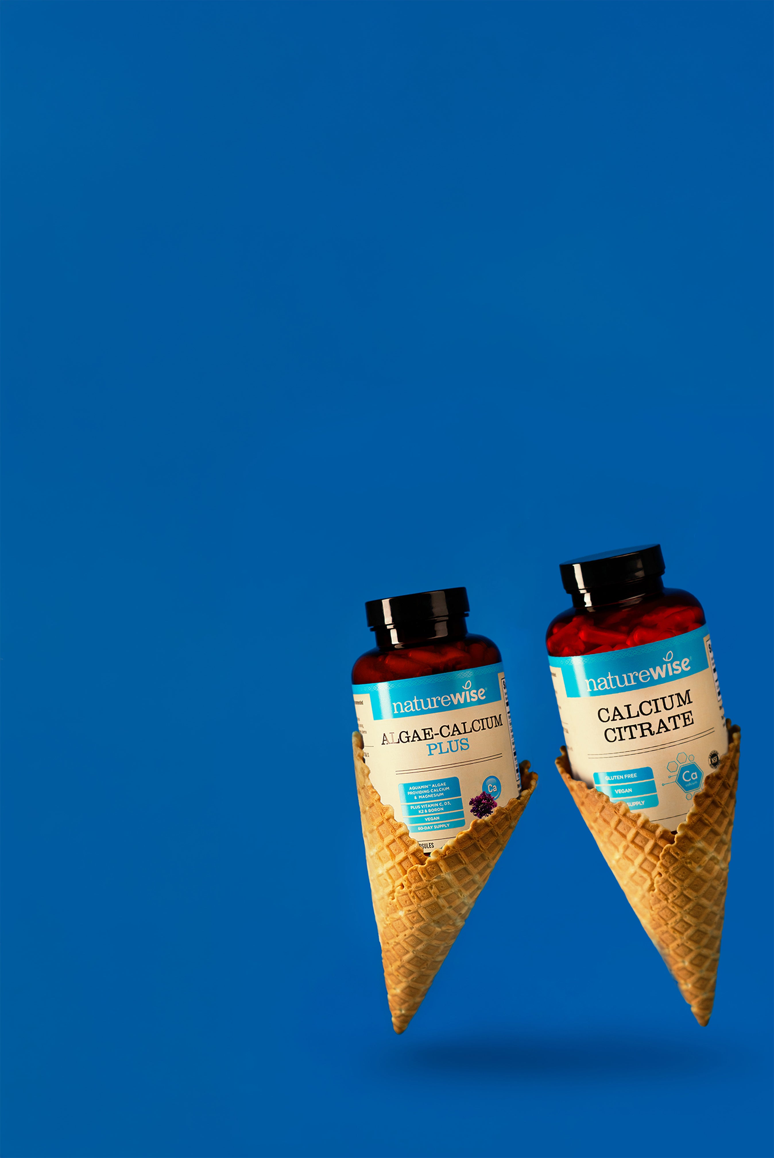 Two bottles of NatureWise calcium supplements in an ice cream cone packaging on a blue background