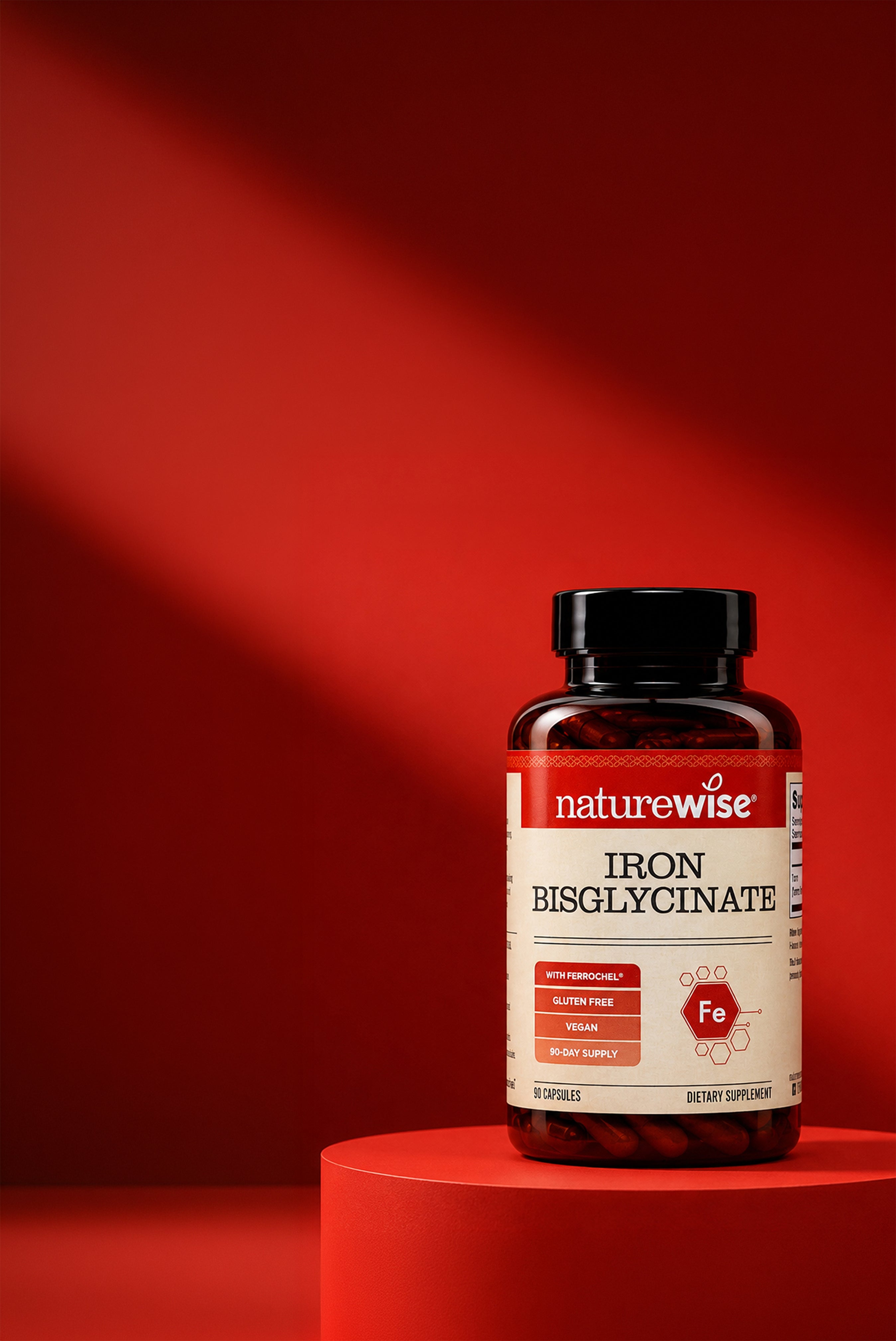 A bottle of Naturewise Iron Bisglycinate dietary supplement displayed on a red cylindrical pedestal against a red background with dramatic lighting.