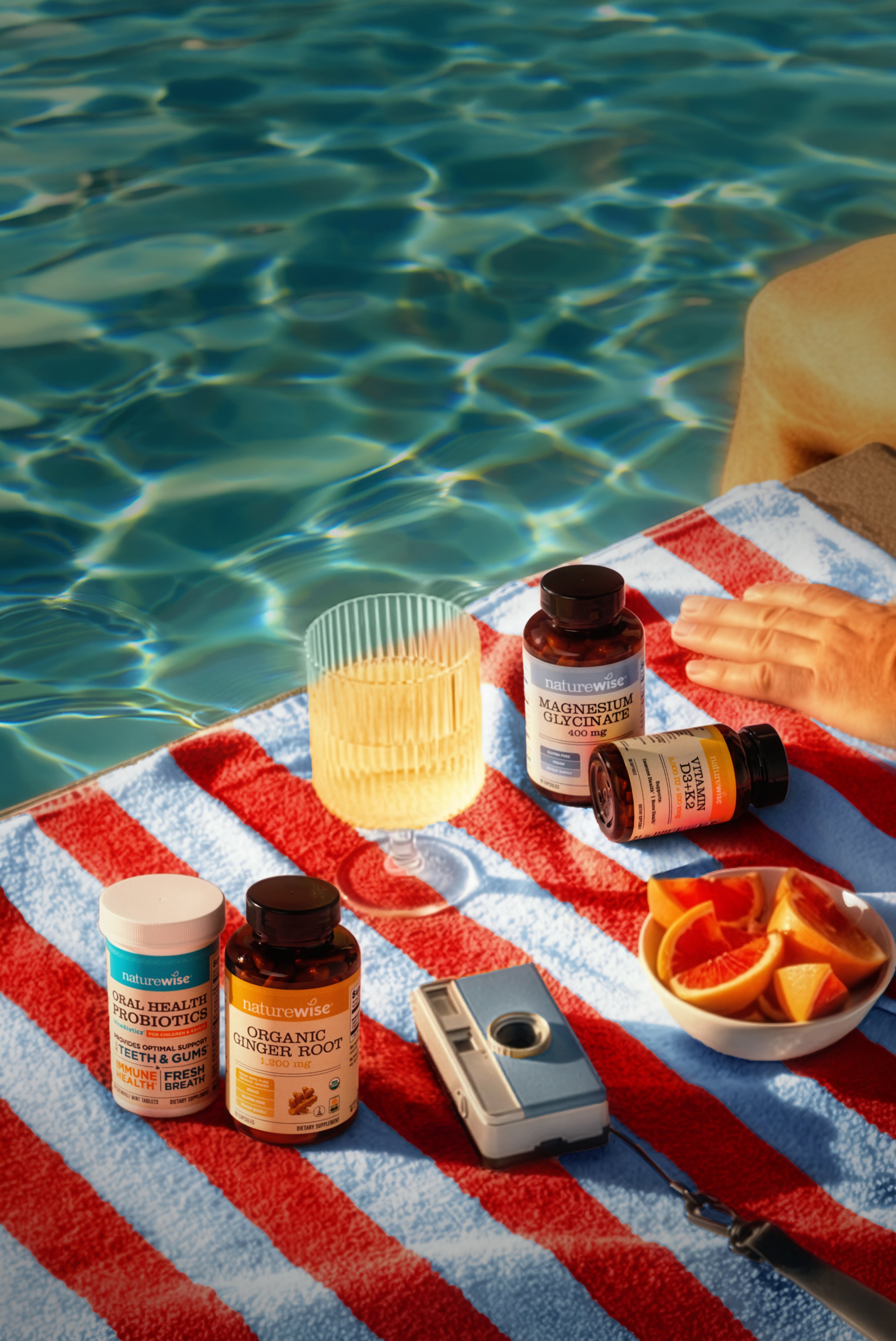 Four NatureWise health supplement bottles arranged on a red and white beach towel by a sunny swimming pool fourth of july.
