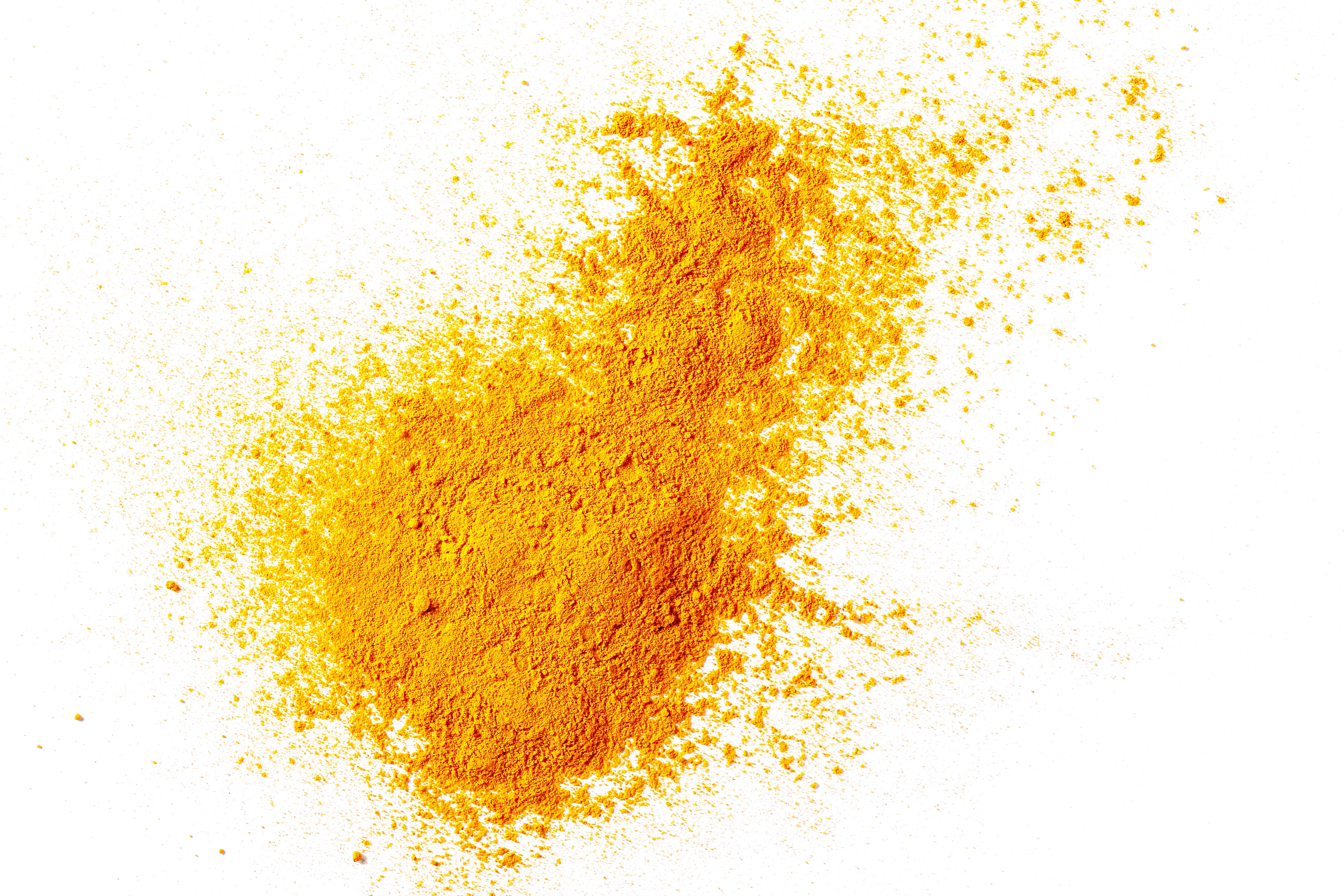 Turmeric root extract raw ingredient as orange powder spread onto a white background.